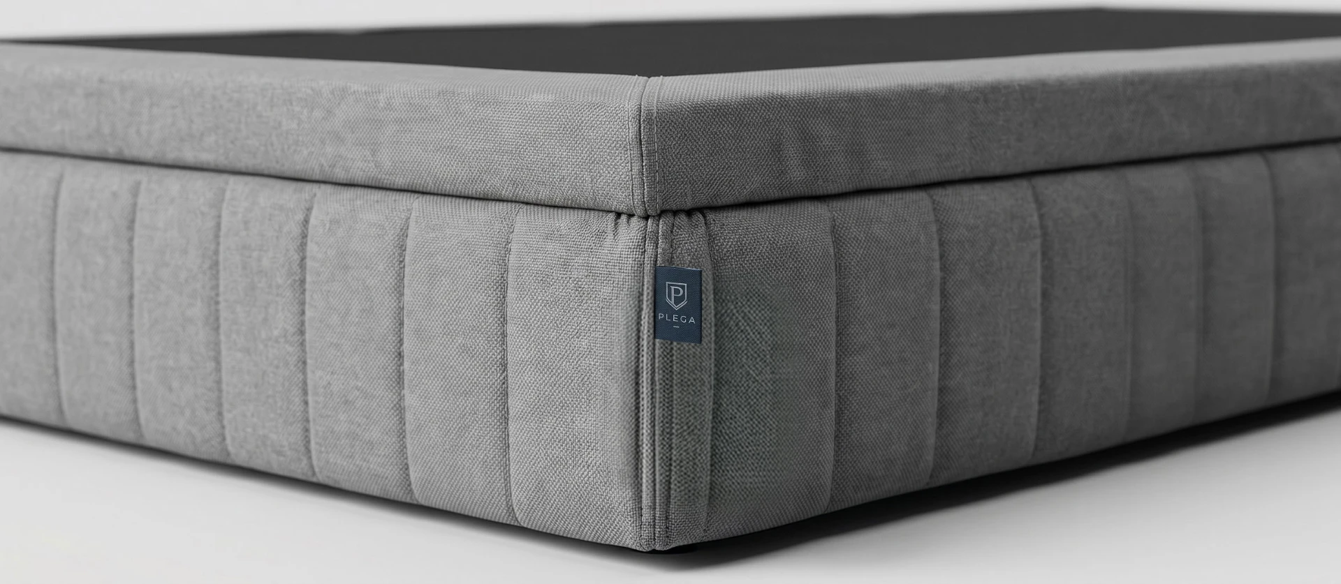 Close-up of the Z-Series 2 grey channel-stitched upholstered base with PLEGA tag